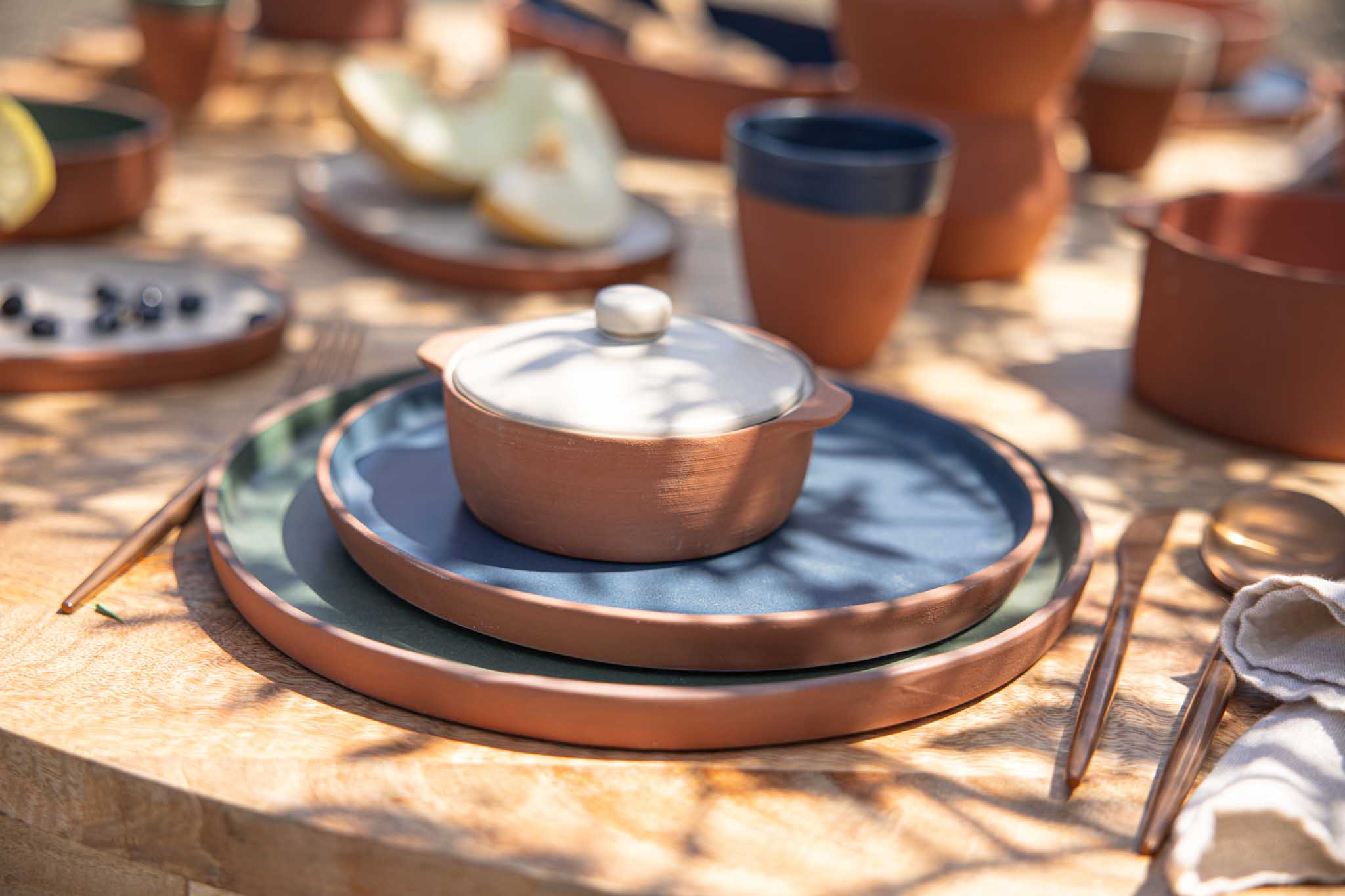 Terracotta dinnerware laid out in dappled sunlight